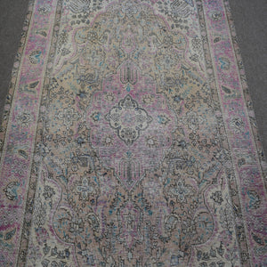 Close up of Persian rug medallion with faded pink and blue floral motifs