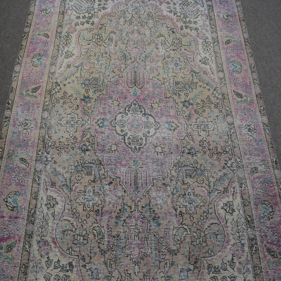 Close up of Persian rug medallion with faded pink and blue floral motifs