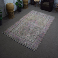 Angled view of hand knotted Persian rug highlighting overall layout and worn vintage character