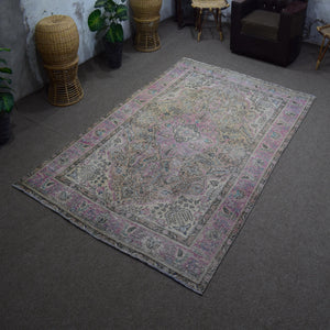 Angled view of hand knotted Persian rug highlighting overall layout and worn vintage character