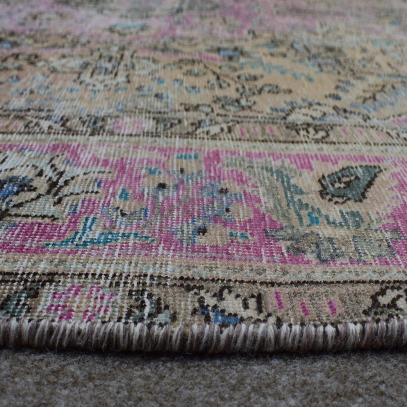 Macro detail of distressed Persian rug weave showing worn wool texture and faded dyes
