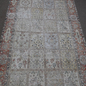Close up of Persian patchwork rug panels featuring floral motifs in soft neutral tones