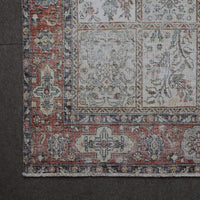 Corner detail of Persian rug showing red border with intricate traditional floral motifs