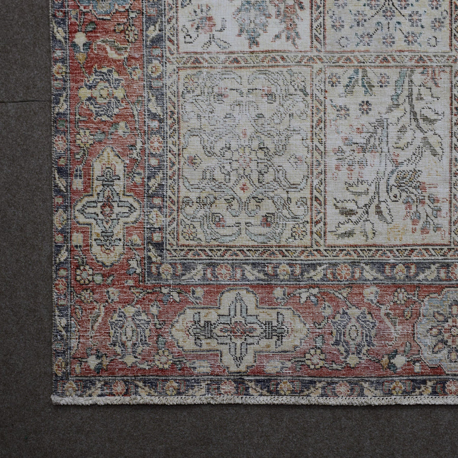 Corner detail of Persian rug showing red border with intricate traditional floral motifs