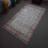 Angled view of hand knotted Persian patchwork rug highlighting overall layout and distressed vintage look