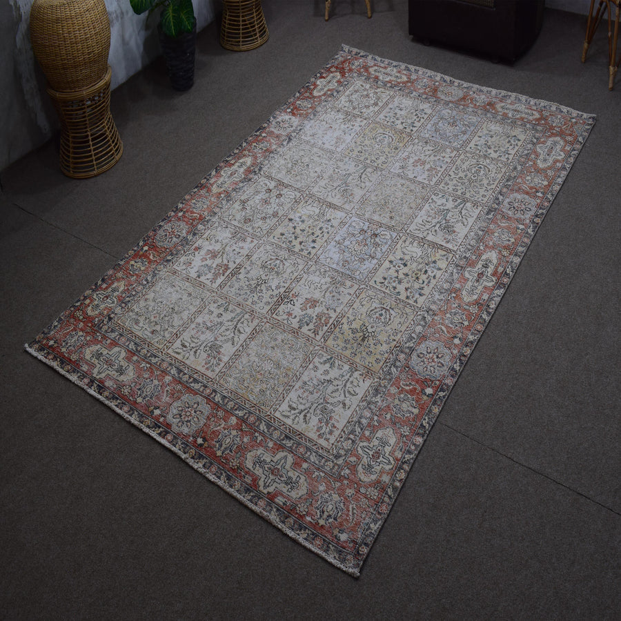 Angled view of hand knotted Persian patchwork rug highlighting overall layout and distressed vintage look