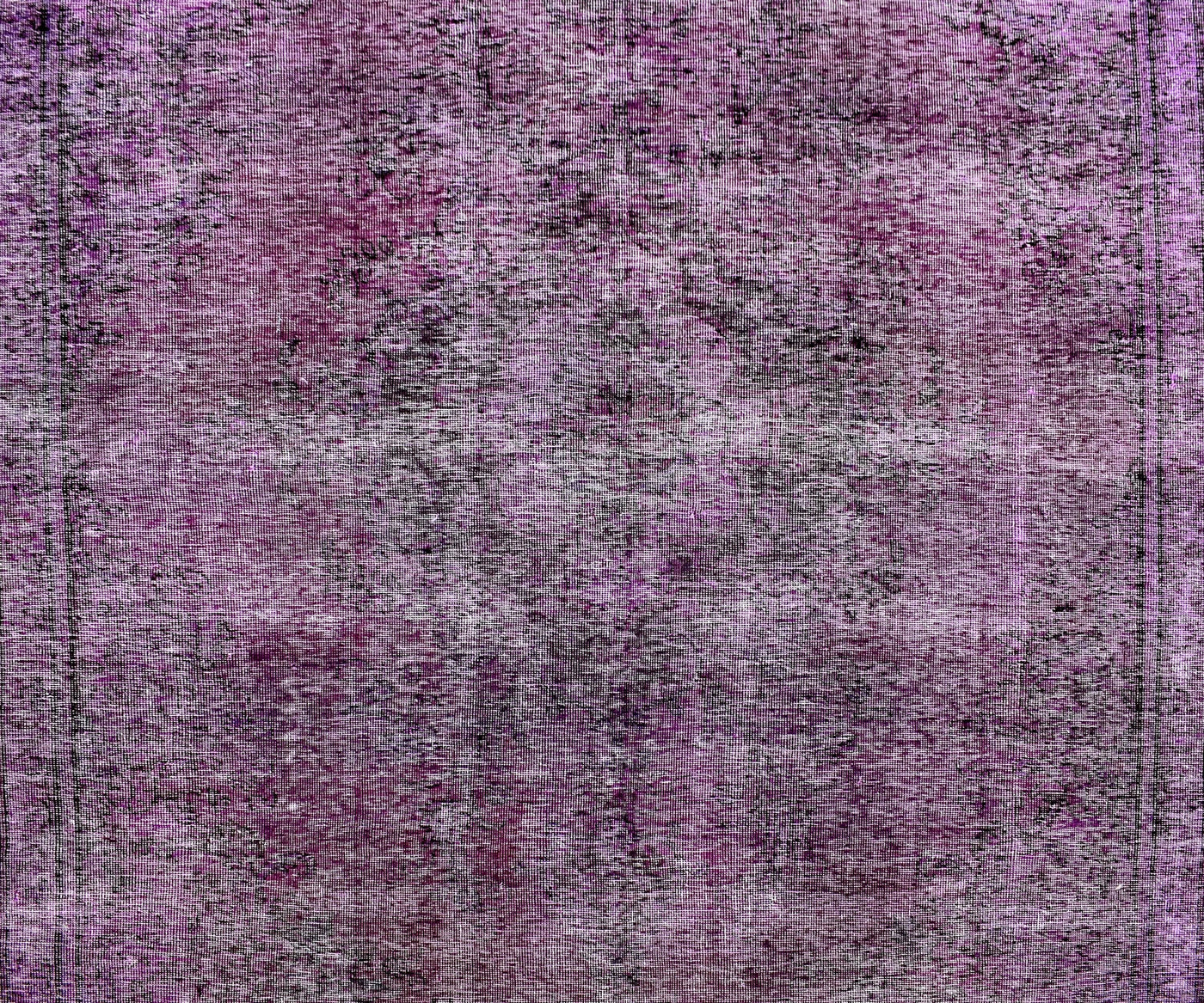 Close-up of overdyed vintage Persian rug showing textured wool pile and mottled purple tones
