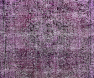Close-up of overdyed vintage Persian rug showing textured wool pile and mottled purple tones
