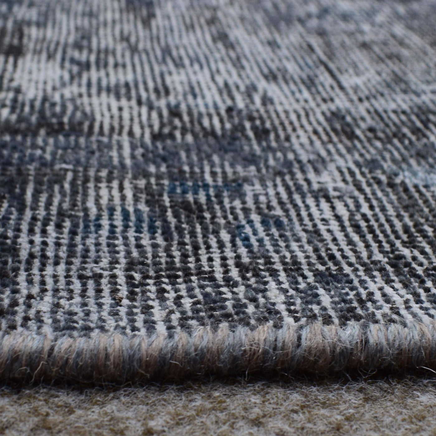 Macro detail of overdyed Persian rug showing dense hand knotted weave structure
