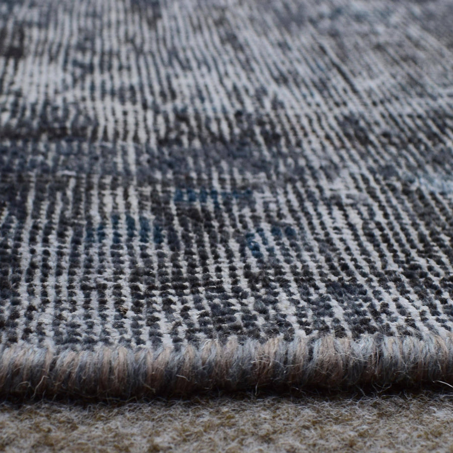 Macro detail of overdyed Persian rug showing dense hand knotted weave structure
